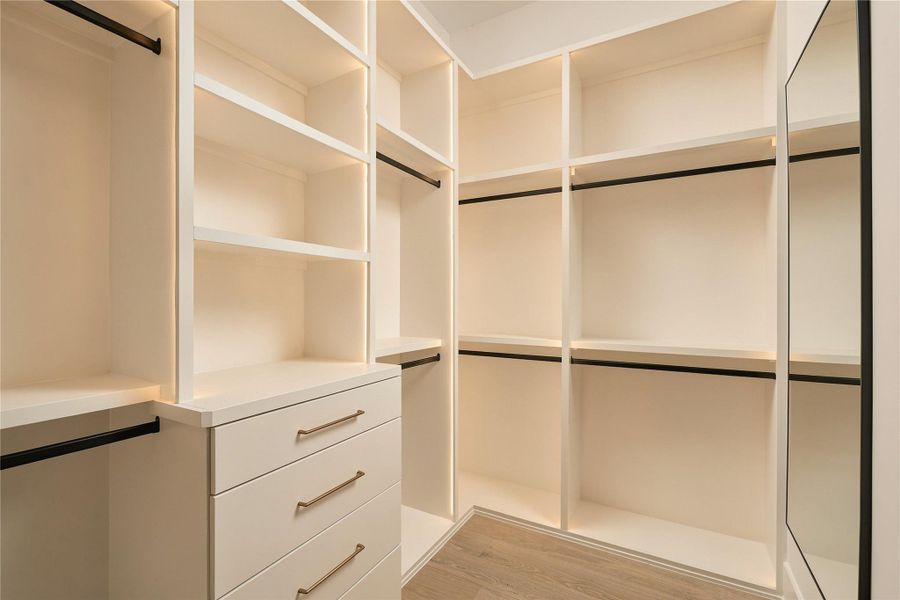 One of two dedicated custom closets in the primary suite offers extensive built-in shelving, drawers, and hanging space, complemented by integrated LED lighting.