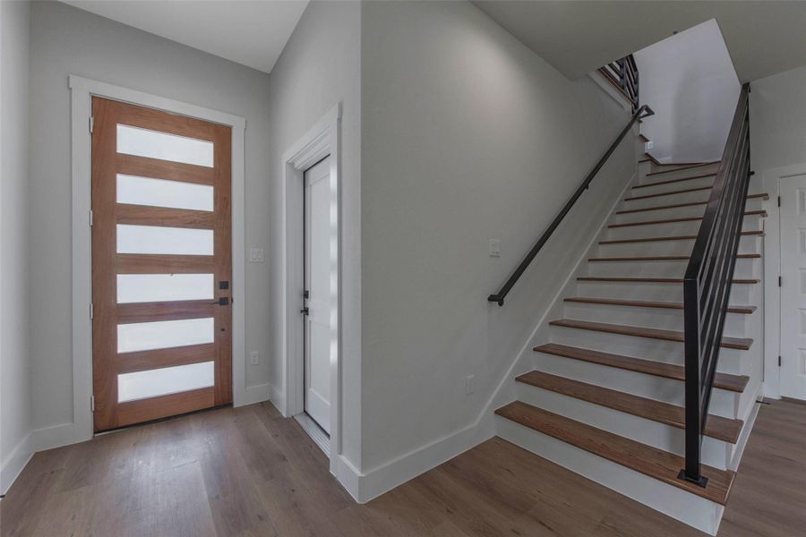 The door to the right leads to a spacious garage with ample room for parking and storage. Glass inserts in the modern front door invite natural light. The door to the right leads to a spacious garage with ample room for parking and storage. Glass inserts in the modern front door invite natural light.