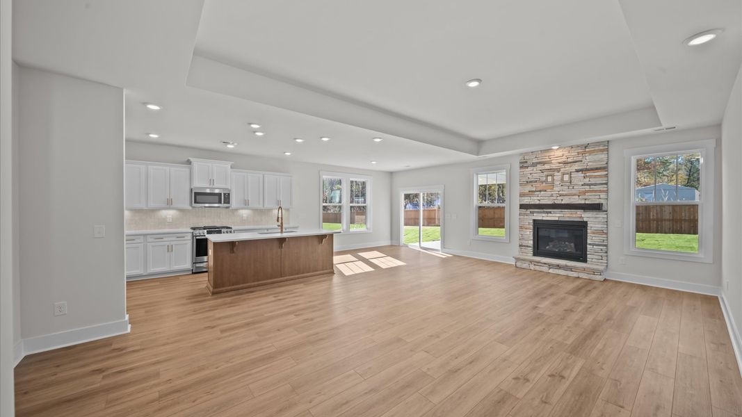 Spacious family room with tray ceiling, rich hardwood flooring, and elegant trim work in a reputable DRB Homes build Spacious family room with tray ceiling, rich hardwood flooring, and elegant trim work in a reputable DRB Homes build
