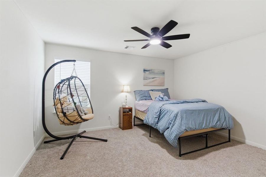 This bedroom features a ceiling fan, a window with blinds, and carpeted floors