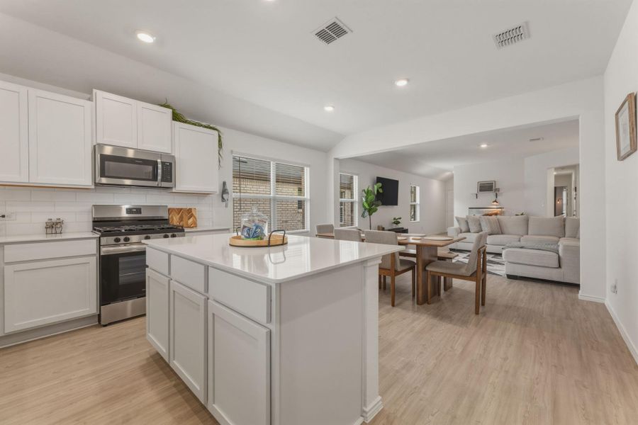 The kitchen features an island with a light-colored countertop, white cabinetry, and stainless steel appliances