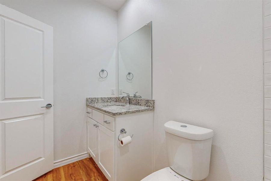 Bathroom with wood-type flooring, vanity, and toilet