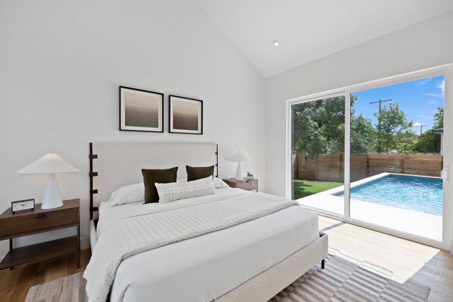 Bedroom with wood finished floors, high vaulted ceiling, access to outside, and recessed lighting Bedroom with wood finished floors, high vaulted ceiling, access to outside, and recessed lighting