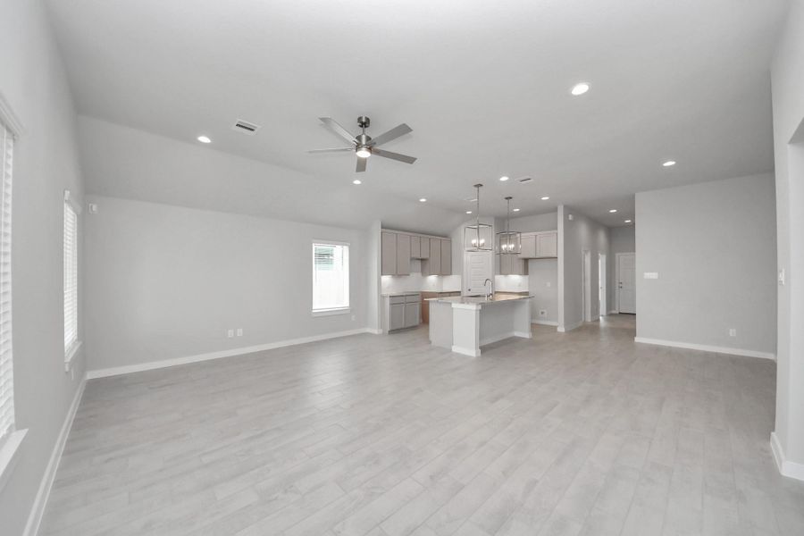 Welcome family and guests to your charming living room! With its high ceilings, recessed lighting, ceiling fan, custom paint, beautiful flooring, and large windows that let in abundant natural light, this room is perfect for gatherings.