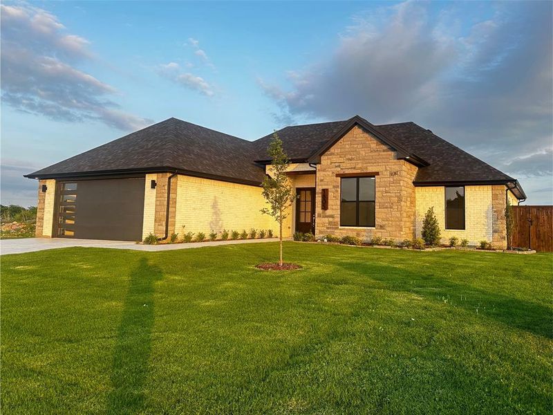 View of front of property with concrete driveway, fence, a shingled roof, and a front yard