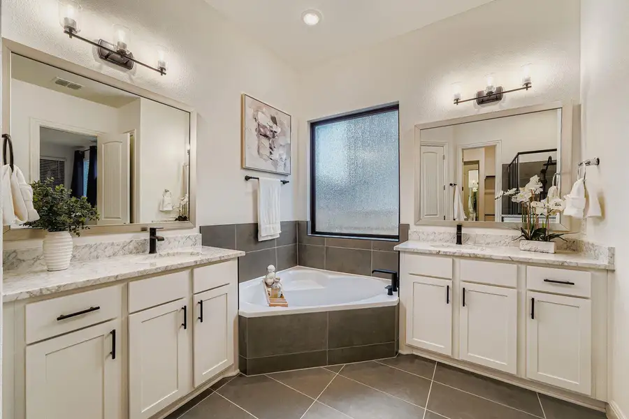 Bathroom with two vanities, a bath, and dark tile patterned flooring Bathroom with two vanities, a bath, and dark tile patterned flooring