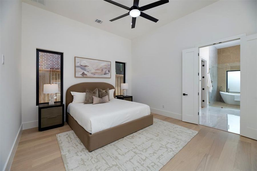Bedroom featuring light wood finished floors, ceiling fan, and ensuite bathroom Bedroom featuring light wood finished floors, ceiling fan, and ensuite bathroom