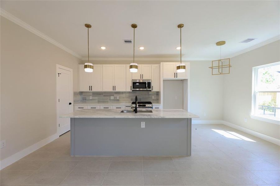 Kitchen offers a large island w/ granite counters & stainless steel appliances.