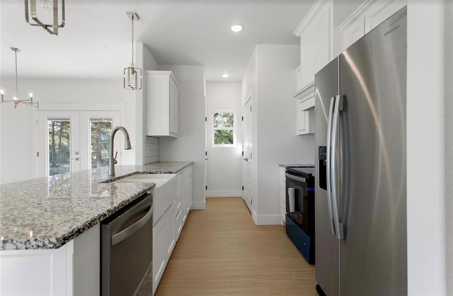 Kitchen featuring white shaker cabinetry, stainless steel appliances, light wood-finish flooring, and white granite countertops Kitchen featuring white shaker cabinetry, stainless steel appliances, light wood-finish flooring, and white granite countertops