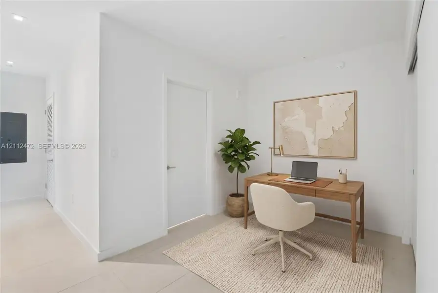 Interior room featuring crisp white walls, neutral large-format tile flooring, recessed ceiling lighting, and a solid-core interior door. VIRTUALLY STAGED
