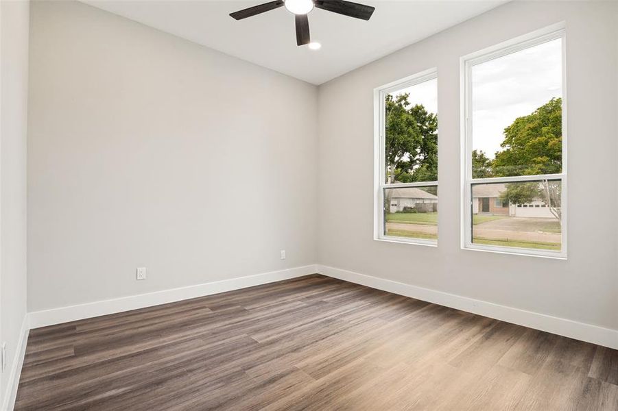 Room featuring wood-finish flooring, white baseboards, and two tall windows with white frames