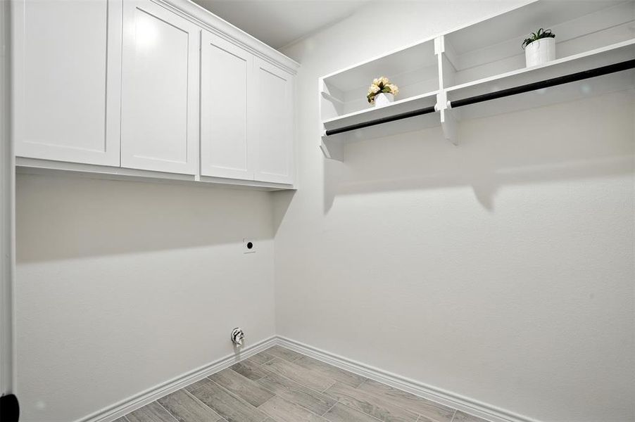 Laundry area featuring light wood finished floors, cabinet space, and hookup for an electric dryer