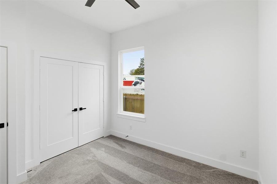 Unfurnished bedroom featuring carpet flooring, a closet, and a ceiling fan