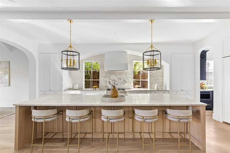 Kitchen featuring a chandelier, arched walkways, light stone countertops, and a kitchen breakfast bar Kitchen featuring a chandelier, arched walkways, light stone countertops, and a kitchen breakfast bar