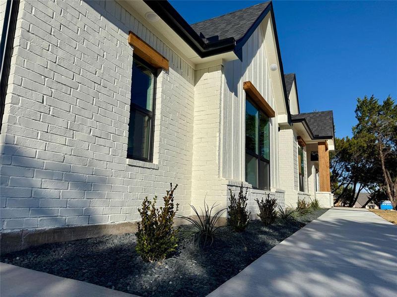 View of property exterior featuring brick siding and roof with shingles