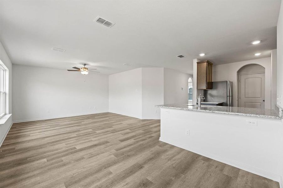 Kitchen featuring light stone countertops, ceiling fan, light hardwood / wood-style flooring, stainless steel fridge, and sink