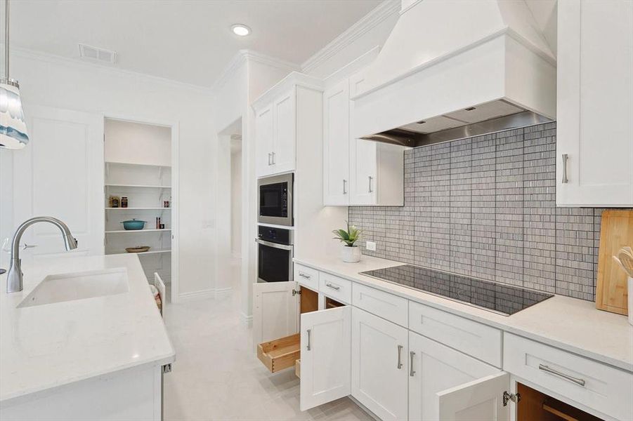 Kitchen with backsplash, stainless steel appliances, custom exhaust hood, sink, and light tile floors