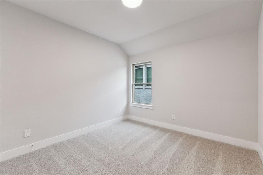 Unfurnished room featuring light colored carpet and vaulted ceiling