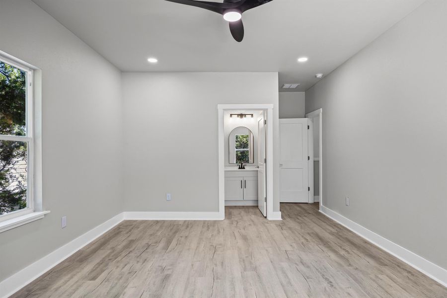 Unfurnished bedroom featuring light wood-style floors, a ceiling fan, recessed lighting, and ensuite bath Unfurnished bedroom featuring light wood-style floors, a ceiling fan, recessed lighting, and ensuite bath