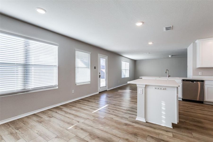 Kitchen featuring a center island, white cabinets, sink, stainless steel dishwasher, and light hardwood / wood-style floors