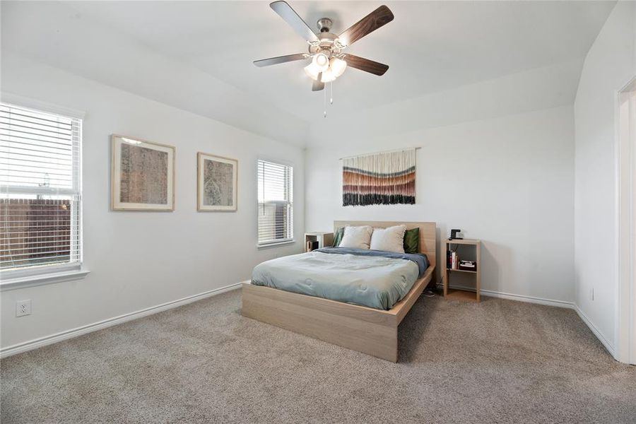 Carpeted bedroom with a ceiling fan and baseboards