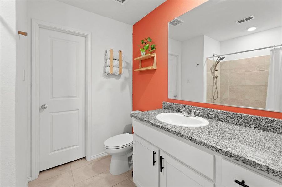 Bathroom featuring vanity, light tile patterned floors, and tiled shower