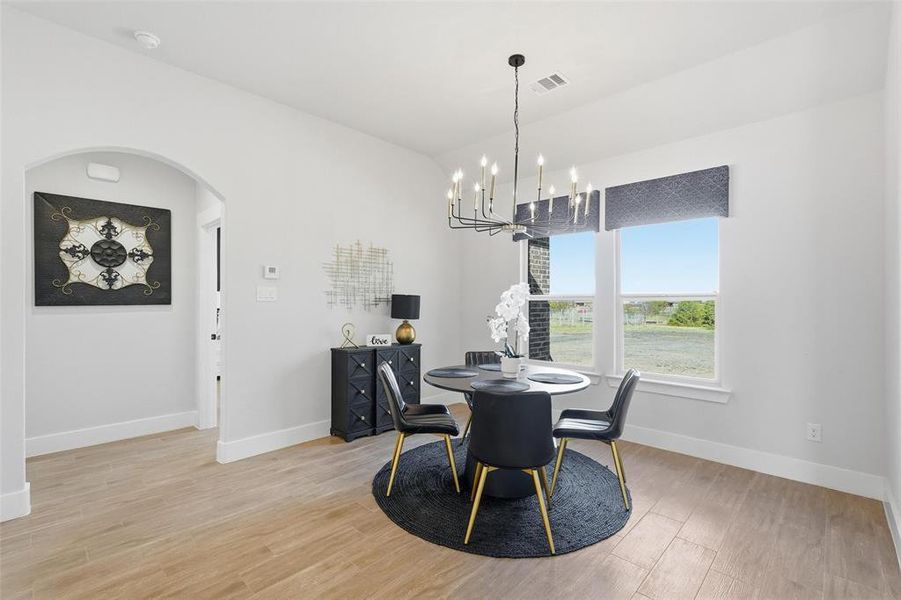 Dining area featuring light wood finished floors, arched walkways, and a chandelier
