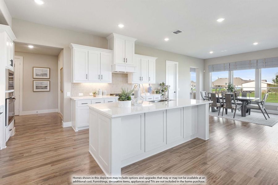 Open kitchen with white cabinets, large center island, and hardwood floors open to dining area