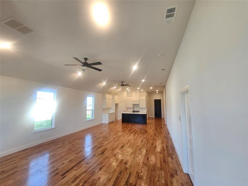 Unfurnished living room featuring ceiling fan, sink, and hardwood / wood-style floors