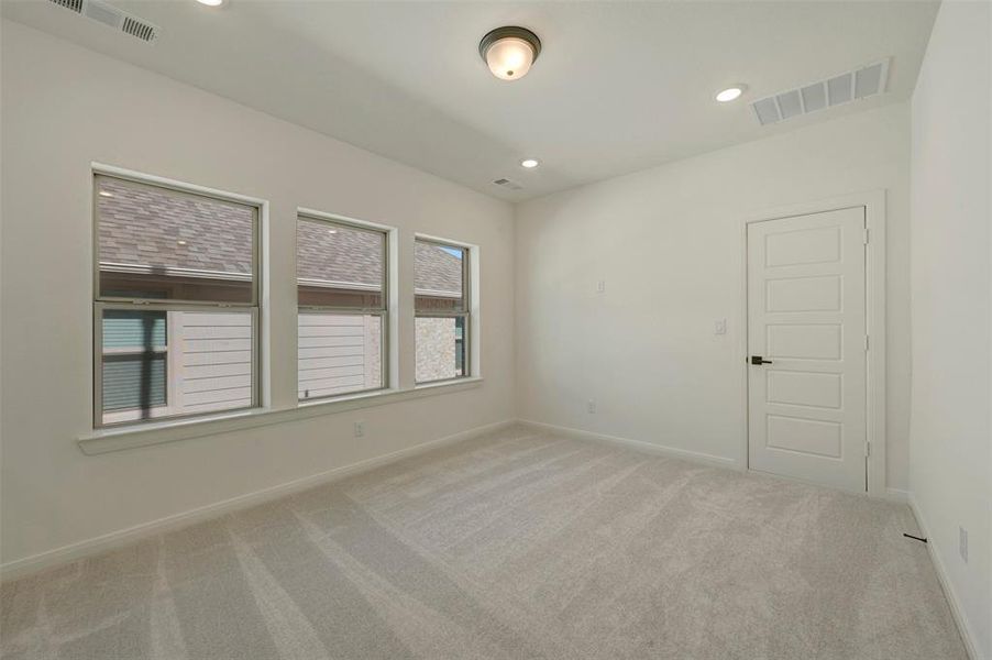 Spacious room featuring light-toned carpeting and multiple windows Spacious room featuring light-toned carpeting and multiple windows