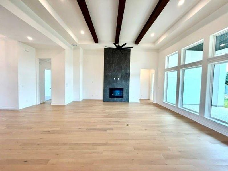 A spacious living area with hardwood floors, a striking fireplace, and expansive windows invites abundant natural light. A spacious living area with hardwood floors, a striking fireplace, and expansive windows invites abundant natural light.