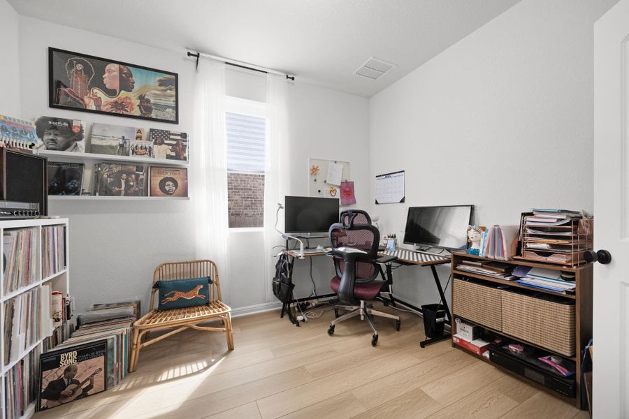 Light-toned wood-finish flooring, white walls, and a single window with white blinds and sheer curtains