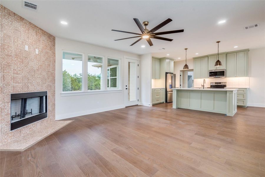 Unfurnished living room featuring a ceiling fan, a high end fireplace, light wood-style flooring, and recessed lighting