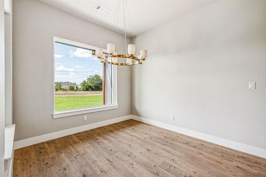 Spare room with a chandelier and light hardwood / wood-style flooring