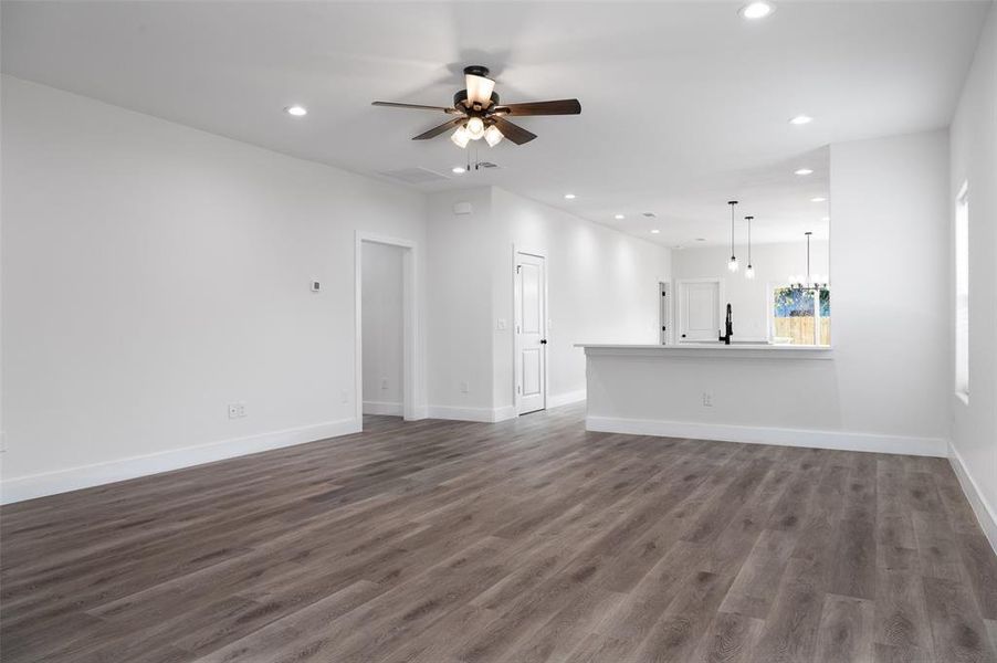 Unfurnished living room with ceiling fan and dark wood-type flooring