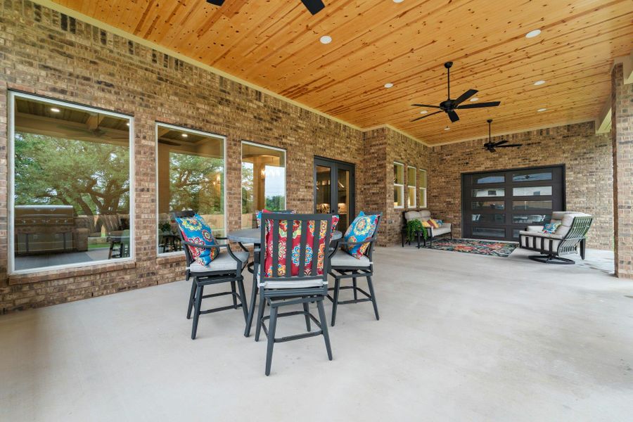 Spacious covered patio featuring a natural wood plank ceiling with recessed lighting and ceiling fans
