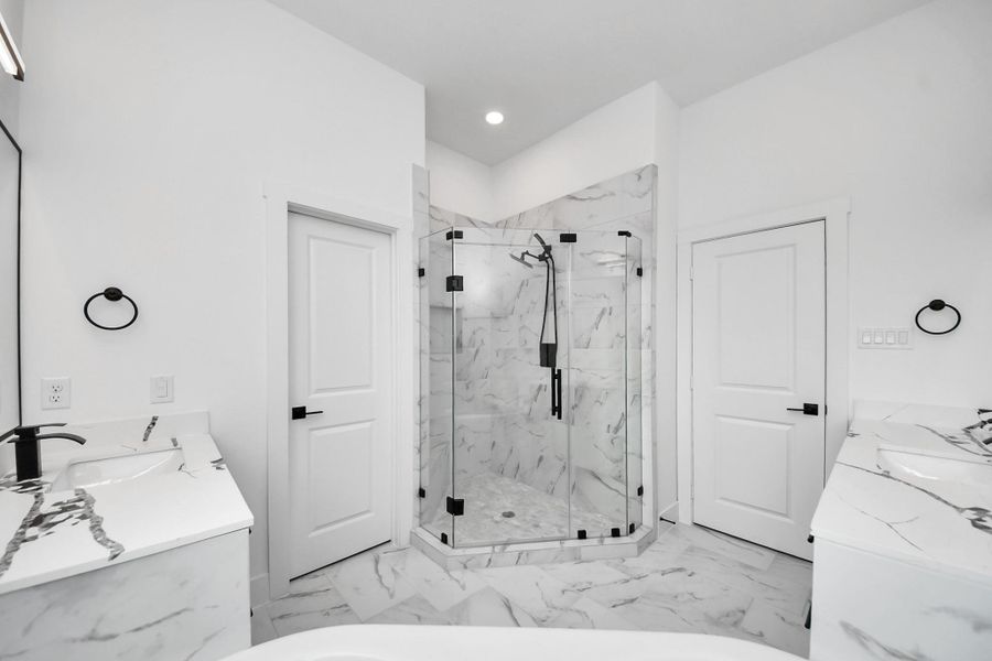 This bathroom features a modern design with sleek marble like surfaces, a spacious glass-enclosed shower, dual sinks with elegant fixtures, and bright, clean lines for a luxurious feel. This bathroom features a modern design with sleek marble like surfaces, a spacious glass-enclosed shower, dual sinks with elegant fixtures, and bright, clean lines for a luxurious feel.