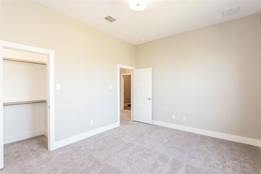 Unfurnished bedroom featuring light colored carpet, a spacious closet, and a closet