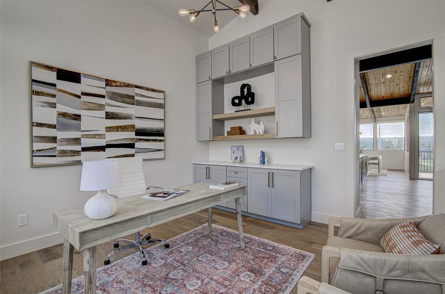 Home office with baseboards, wood finished floors, and vaulted ceiling Home office with baseboards, wood finished floors, and vaulted ceiling