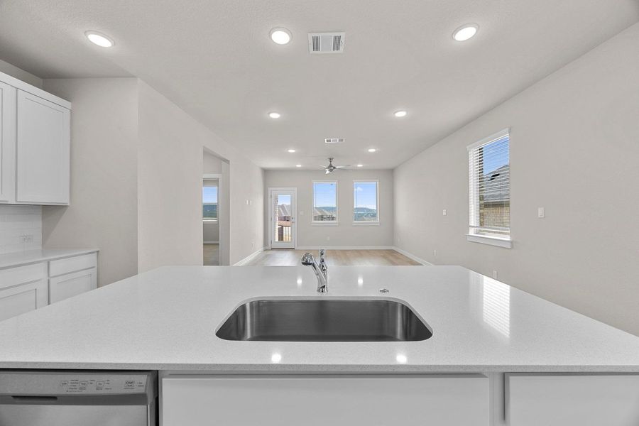 A well-lit kitchen with sleek countertops and an open-concept living area with plank flooring. A well-lit kitchen with sleek countertops and an open-concept living area with plank flooring.