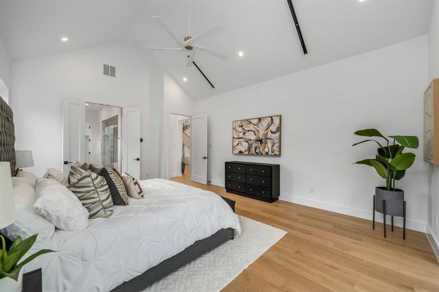 Bedroom with high vaulted ceiling, light wood-type flooring, a ceiling fan, recessed lighting, and ensuite bathroom