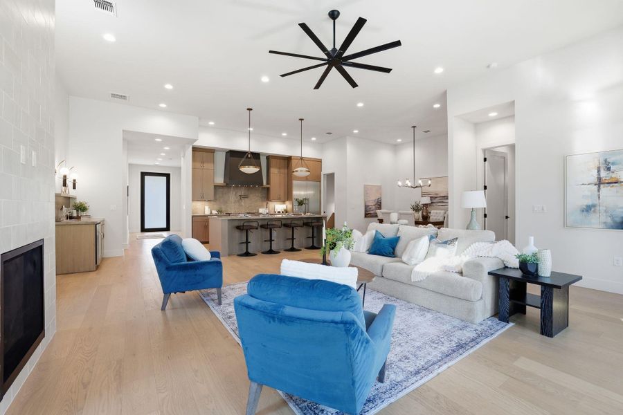 Living room with recessed lighting, light wood-style floors, a tiled fireplace, and ceiling fan