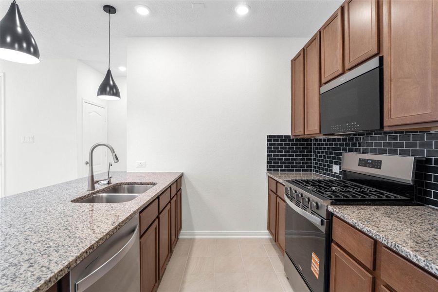 Additional photo provides a closer look at the gorgeous Granite countertops in Caramel Cream, Woodmont Cody cabinetry, Daltile Artezen backsplash in Deep Blue, Oden pendant lighting in Navy, and Whirlpool stainless steel appliances. Additional photo provides a closer look at the gorgeous Granite countertops in Caramel Cream, Woodmont Cody cabinetry, Daltile Artezen backsplash in Deep Blue, Oden pendant lighting in Navy, and Whirlpool stainless steel appliances.