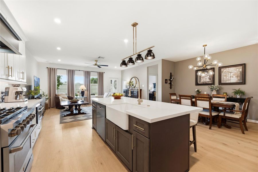 Open-concept kitchen, dining and living area with a large quartz island, custom hardwood cabinetry and glue-down hardwood flooring across the main living spaces.
