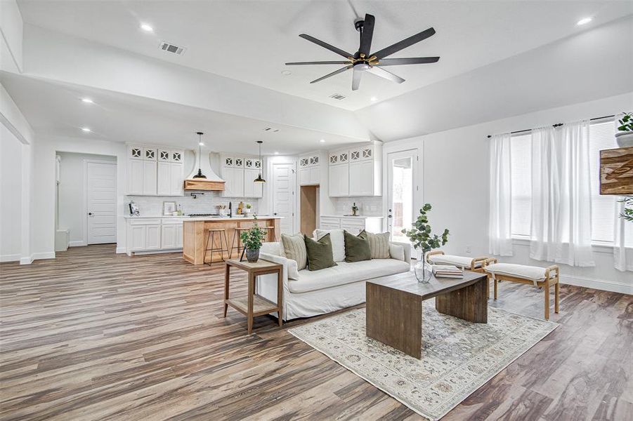 Living room featuring light hardwood / wood-style floors, vaulted ceiling, and ceiling fan