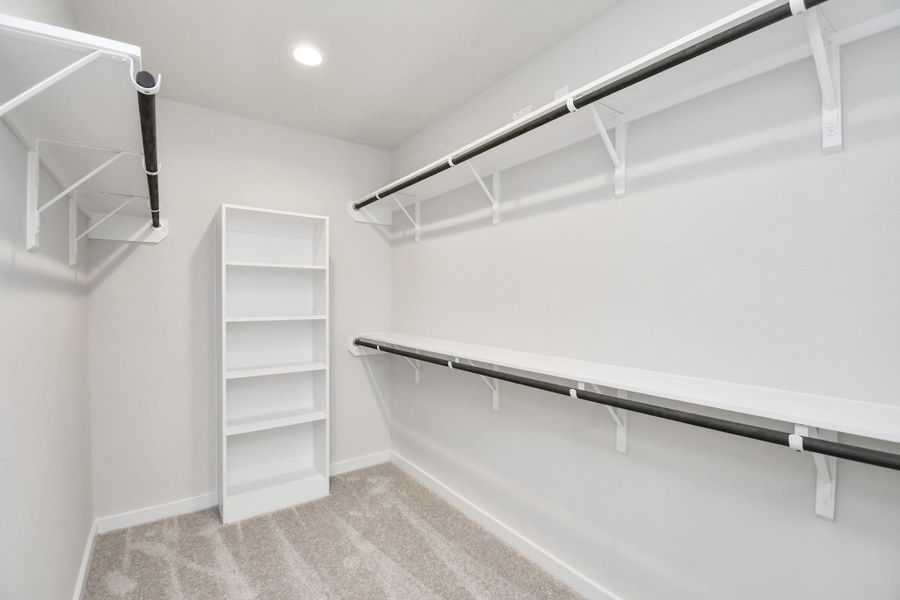 Immerse yourself in the lap of luxury within this roomy walk-in closet boasting high ceilings, built in shelves, and plush carpeting. Sample photo of completed home with similar floor plan. Actual colors and selections may vary. Immerse yourself in the lap of luxury within this roomy walk-in closet boasting high ceilings, built in shelves, and plush carpeting. Sample photo of completed home with similar floor plan. Actual colors and selections may vary.