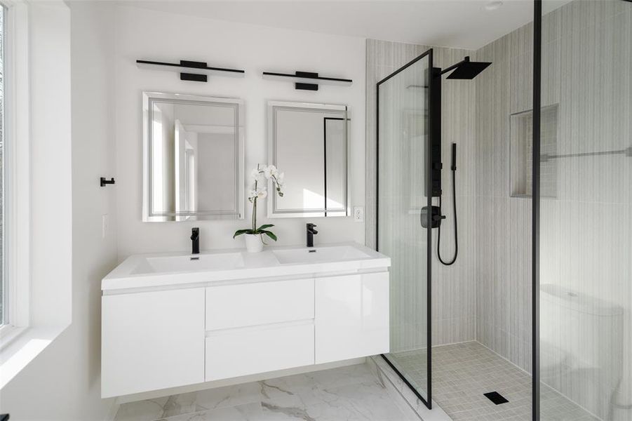 Full bath featuring marble finish floor, a sink, and a shower stall