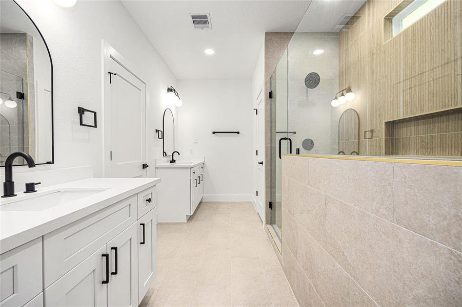 Primary Bedroom-This bathroom features a modern design with dual sinks, sleek black fixtures, and a spacious glass-enclosed shower. The neutral color palette and ample lighting create a bright, inviting space.