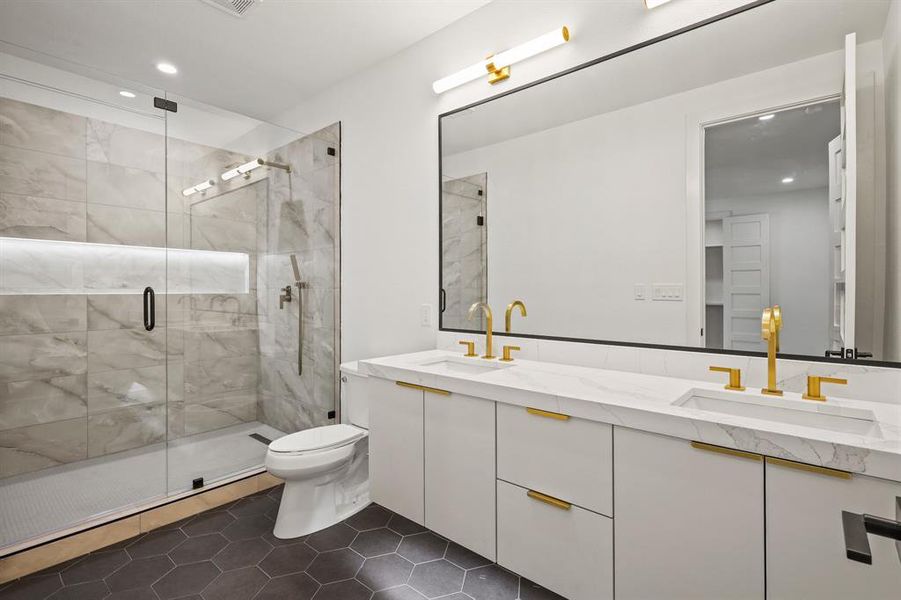 Bathroom featuring toilet, tile patterned flooring, double vanity, and a shower with door