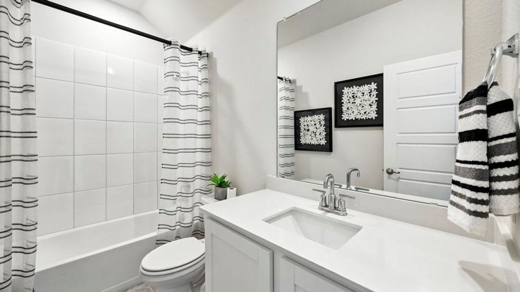Bathroom featuring a white vanity with an integrated sink, a large mirror, and a shower-tub combination with white tile surround